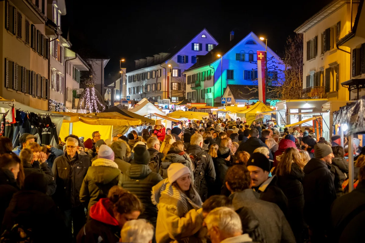 Man sieht eine grossen Menschenansammlung und Dächer von Pavillons. 